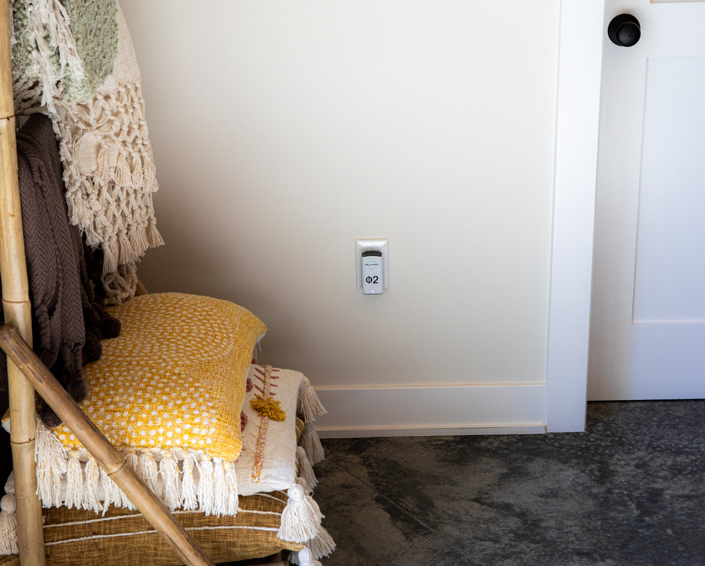 EMF PROTECTION  - Photo of a Blushield Phi 02 Plugin plugged into an outlet in a room next to pillows